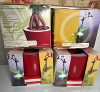 Four boxed Spotlight Green illuminated planters stacked, showing three red and one green planter boxes.