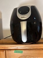 Front view of black Intertek Power Air Fryer XL with silver handle on wooden surface.