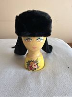 Front view of black winter hat with faux fur on a painted mannequin head.
