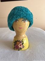 Teal fuzzy ladies hat displayed on a painted wooden mannequin head