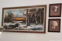 Full view of the large framed oil painting and two smaller framed vintage prints hanging on the wall.