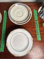 Photo of a white saucer with gold decorative elements and blue rim, part of the orphaned saucers