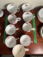 Top-down view of eight orphaned tea cups showing floral patterns inside the cups.