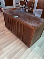 Wooden cedar chest from an angle showing the top and one side with visible wear and surface marks.