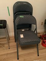 Set of 4 foldable chairs stacked and one unfolded showing full chair, dark gray metal frame with blue-gray patterned fabric upholstery