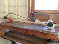 Full-length view of the gas trimmer on wooden bench with manual and spool beneath