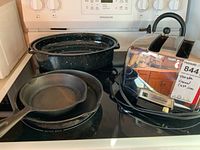 Photo showing the Sunbeam toaster, whistling tea kettle, enamel roaster, and cast iron fry pans arranged on a stovetop.