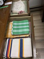 Drawer with folded linens including striped tea towels and placemats in various colors