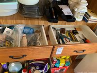 Two wooden drawers filled with various utility items and tools.