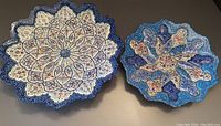 Top view of both enamelled metal plates showing the detailed Persian designs and various shapes.