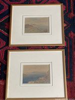 Two small framed watercolour paintings by Samuel Lucas, shown side by side, resting on a patterned textile.