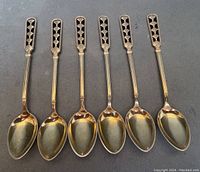 Six coffee spoons laid out row showing gold wash bowls and black enamel decorated handles