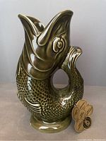Olive green ceramic fish form gurgle jug with attached Dartmouth Pottery tag