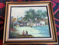 Framed original painting showing village scene with trees, houses, and two figures in foreground.