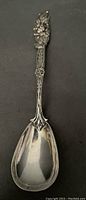 Top down view of the spoon's handle and bowl showing the floral pattern and silver finish.