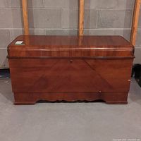 Front view of cedar chest showing wood grain and keyhole in center with visible surface wear.