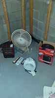 Full view of the lot with heaters, fan, thermometers and hygrometers on concrete floor against wall