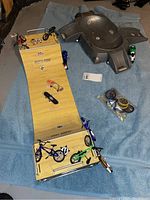 Two Flick Trix wood ramps shown with multiple miniature bicycles, motorcycles, and finger skateboards arranged on and around ramps on a blue towel background.