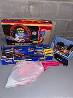 Majorette Turbo Loop Track box and various track parts and toys on concrete floor