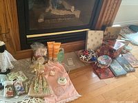 Wide view of lot items arranged on floor including shower gel tubes, potpourri bags, rings dish, various floral decorated boxes and journals, stick-on bows and tissue packages.