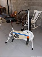 Side view of Sears Shape Shop stationary bike showing white frame, padded black seat, and pedal mechanism with blue and orange stripes.