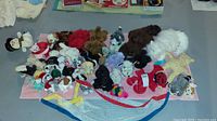 View of many stuffed animal toys arranged on a floor with visible variety of animals and character plushies.