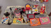 Overview of the toy lot showing multiple vintage toys such as cash register, Play-Doh, Etch A Sketch, toy fire truck, tape recorder, and others.