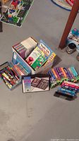 Boxes with multiple VHS tapes and books arranged inside and outside of open boxes, showing children's entertainment and educational items.