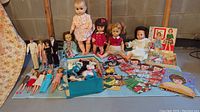 Wide view of all dolls, cutouts, clothing box and accessories on floor