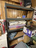 Frontal view of the shelving unit filled with various household items and boxes, including transparent plastic containers and Epson box, showing general condition and context.
