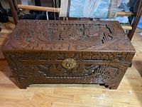 Front and top view of the carved wooden chest with nautical scenes and floral motifs on the lid and front panel.