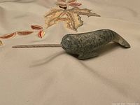 Full side profile of the carved stone narwhal showing green speckled texture, polished surface, and spiral tusk.