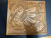 Front view of the carved wooden heron panel showing the detailed indigenous style carving and textured background.