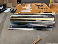 Stack of LP vinyl records viewed from the side showing thickness and variety of albums in the lot.