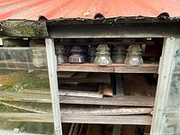 Photo showing multiple glass insulators arranged on wooden shelves behind glass panels, highlighting range and storage.