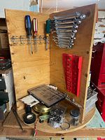 Front view of rotating plywood tool organizer loaded with tools including screwdrivers and combination wrenches
