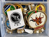 Top view of tote containing various enamel cast metal naval crest plaques