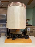 Front view of the vintage lamp with ceramic jaguar and fabric lampshade on wood base.