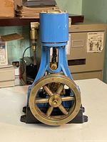 Front view showing blue cylinder, brass flywheel and black cast iron base