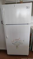 Full front view of white Frigidaire refrigerator with floral decal on lower door.
