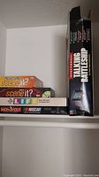 Shelf photo showing boxes of Electronic Talking Battleship, Scene It? editions, The Game of Life, and Monopoly NASCAR edition stacked