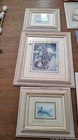 Three Southwest art prints framed in whitewashed pale pink frames with varying sizes laid out on floor.
