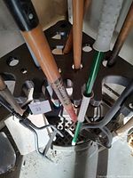 Overhead view of various yard tools stored in a black plastic tool organizer rack showing handles and tool types.