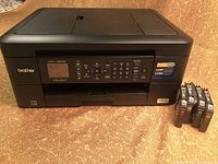 Front view of Brother multifunction printer showing control panel and display with four refillable ink cartridges next to it.