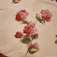 Close-up showing detailed pink hydrangea flowers and green leaves printed on white cotton fabric.