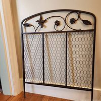 Front view of the decorative metal screen showing the full panel with bird and floral designs at the top.