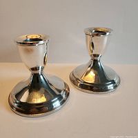 Front view of both polished sterling silver weighted candlesticks together.