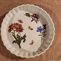 Top-down photo showing the fluted edges and detailed floral and butterfly designs inside the ceramic quiche pan.