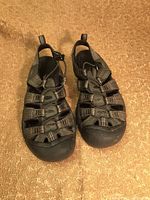 Pair of black and grey Keene sandals on carpeted floor showing front and side views of the sandals, highlighting the closed toe design and multiple straps