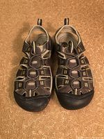 Photo showing the pair of brown and beige Keene sandals with multiple straps and protective toe caps on a carpet floor.